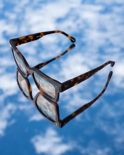 Dos monturas de acetato reflejadas sobre una superficie azul